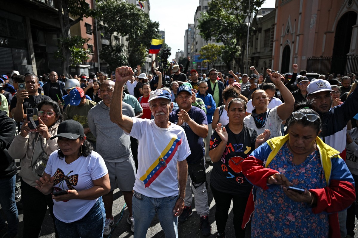 Mobilização popular no entorno do Palácio Miraflores, sede do governo venezuelano | Crédito: Federico PARRA / AFP FacebookWhatsAppEmailXCompartilhar O bombardeio aéreo do governo Donald Trump, dos EUA, na madrugada deste 3 de janeiro de 2026, ao território venezuelano, para sequestrar o presidente Nicolás Maduro e sua esposa, Cília Flores, a fim de forçar pelas armas uma mudança de regime, viola a soberania da América Latina e tem um profundo significado para o Brasil e o mundo. A intervenção armada, e também a reação venezuelana em curso, marcam uma inflexão nas relações internacionais em escala mundial. O governo bolivariano segue de pé. Antes de tudo, o ataque militar na Venezuela marca uma nova etapa da guerra imperialista de intervenção e espoliação da América Latina sob o Corolário Trump. A guerra híbrida que se prolongava há mais de 25 anos culminou nessa madrugada em uma ação militar direta e sem máscaras. Consiste em uma tentativa de derrubar o projeto de independência política do povo venezuelano e representa um recado aos demais povos e governos da região de que devem se manter subordinados e dependentes de Washington pela via do terror, do medo, da instabilidade institucional promovida pelos Estados Unidos. Os alvos dos bombardeios explicitam uma tática precisa de atingir a unidade cívico-militar, principal base de sustentação do governo bolivariano. O objetivo estratégico não está oculto. O establishment estadunidense quer atingir dois objetivos com um único movimento. Por um lado, eliminar um governo independente que dá exemplo de resistência ao imperialismo na região para apropriar-se diretamente das riquezas naturais e energéticas venezuelanas, especialmente das maiores reservas provadas de petróleo do mundo. Por outro, quer impedir que a China, país eleito rival hegemônico, importe esse importante combustível e fonte de energia para o desenvolvimento, sendo que o país asiático é o destino de 80% das exportações venezuelanas. Vejamos como a tática dos bombardeios desse dia 3 de janeiro revelam a estratégia estadunidense. Alguns dos locais foram o Forte Tiúna e a base aérea de La Carlota, o Comando-Geral da Milícia Bolivariana (ao lado do Quartel da Montanha) e o Porto de La Guaira. Esses lugares representam uma mensagem muito clara: atingir simultaneamente as bases de sustentação civil e militar do governo bolivariano da Venezuela e afetar, indiretamente, a China. Em primeiro lugar os alvos das Forças Armadas. Os bombardeios atingiram o Forte Tiúna e a Base Aérea de La Carlota. O Forte Tiúna, principal e mais importante instalação militar da Venezuela, localizado em Caracas, sede do Ministério da Defesa, do Comando Estratégico Operacional da Força Armada, da Academia e a Universidade Militar Bolivariana, o Batalhão Ayala, a Corte Marcial e os tribunais militares. Atacar esse alvo significa que os EUA ativaram um plano para derrubar o principal centro de decisão militar estratégica do governo venezuelano. A Base Aérea de La Carlota, localizada no coração de Caracas, é um aeroporto militar e centro logístico de comando para operações para a proteção da Capital do país. É ponto de entrada e saída de equipamentos e tropas para a defesa do centro político, sendo também importante instalação de defesa da Capital. Com isso, os ataques vulnerabilizam duas das principais instalações militares da capital venezuelana. Em segundo lugar, o Comando Geral da Milícia Bolivariana é a sede da resistência civil armada. Responsável pela defesa territorial em união cívico-militar, mobilizando a população civil em apoio às FAN regulares. A Milícia bolivariana tem mais de 4 milhões de alistados, podendo esse contingente ser duplicado, com formação em técnicas de guerra assimétrica. Sua sede fica a poucos metros do Quartel da Montanha, ou Quartel do 4F, lugar histórico para a Revolução Bolivariana. Foi de lá que Hugo Chávez liderou uma rebelião contra o neoliberalismo, em 4 de fevereiro de 1992. Localizado no seio da mais tradicional e uma das mais populosas comunidades ou favelas caraquenhas, o complexo 23 de Janeiro, é o local que abriga os restos mortais do líder Hugo Chávez. Com vista frontal, está posicionado a menos de dois quilômetros do centro do poder político nacional venezuelano, o Palácio Presidencial de Miraflores. Esse lugar é um dos principais espaços simbólicos da resistência do povo venezuelano e também um dos pilares de sustentação popular ao governo bolivariano, abrigando população trabalhadora da Capital. Junto com os militares leais, os civis populares reverteram o golpe de estado consumado em 11 de abril de 2002. Finalmente, em terceiro lugar destaco o bombardeio do Porto de La Guaira, distante apenas 31 quilômetros da Capital e localizado nas adjacências do principal aeroporto do país, o Aeroporto Internacional de Maiquetía. La Guaira não é o principal porto de exportação de petróleo. Sua função principal é abastecer com suprimentos médicos, bens de consumo e manufaturados a capital venezuelana. Bombardear o Porto de La Guaira significa um recrudescimento ao bloqueio comercial e neutralização de uma fonte de abastecimento da Capital do país, que concentra o poder político, militar e social venezuelano. É um sinal que preparam condições para um asfixiamento posterior e prolongado, dando continuidade ao bloqueio e cerco que já estava em vigor, mas com maior violência. Em pesquisas anteriores encontrei evidências históricas de que o governo bolivariano da Venezuela tem como pilar fundamental a unidade cívico-militar, representada sobretudo pelo subproletariado urbano e pelos militares bolivarianos. O ataque militar estadunidense desta madrugada atinge o coração das forças mais fundamentais de sustentação tanto civis quanto militares do governo venezuelano. É, portanto, uma tentativa armada aberta de derrubada do regime bolivariano. Mas o governo não caiu. Segue com apoio interno e externo. O presidente Maduro e sua esposa, Cília Flores, foram sequestrados e estão a caminho dos EUA. Segundo o general Dan Caine, chefe do Estado Maior estadunidense, estão sendo levados de navio para serem “julgados” por “narcoterrorismo” nos EUA, um crime não tipificado no Direito Internacional e uma flagrante ilegalidade, além de um ato brutal e imoral de violação de direitos humanos e da soberania venezuelana. Resistência de militares e do povo A reação e resistência venezuelana também deve ser analisada em seu significado histórico já nessas primeiras horas. Militares leais e o povo estão se mobilizando em todas as partes do país. A liderança da resistência está sendo protagonizada politicamente por uma mulher, a vice-presidenta Delcy Rodríguez, uma mulher socialista. E pelo ministro do Interior, Justiça e Paz, Diosdado Cabello, que lidera as forças militares leais. A rede Telesur de televisão transmite os manifestos de apoio popular e militar e o pedido das ruas de devolução e regresso de Maduro e Cília ao país. É bom lembrar que o povo venezuelano protagonizou a guerra de independência no início do século 19. Entregou enorme sacrifício à causa da libertação da América e venceu. E derrotou também inúmeras tentativas de golpe de Estado. Porém, um ataque militar desta magnitude é uma novidade em mais de 100 anos de história do país. Essa violência imperialista pode representar uma inflexão histórica em toda a região. O ataque está provocando um rechaço imediato de governos de diversos países e movimentos sociais ao redor do mundo. Todos repudiando os ataques e denunciando sua ilegalidade, que fere o direito internacional, e são atos brutais e imorais. O presidente Lula, a presidenta Claudia Sheinbaum, do México, e o presidente Gustavo Petro, da Colômbia, lideram como presidentes de países latino-americanos um forte repúdio, junto com Cuba. O presidente Emmanual Macron declarou que o sequestro do presidente Maduro viola a legislação internacional. O primeiro-ministro espanhol, Pedro Sánchez, diz que a violação do direito internacional por parte dos EUA é inaceitável. O MST convocou manifestações de apoio ao povo venezuelano no Brasil. É momento de todos e todas defendermos a soberania do povo venezuelano e rejeitarmos firmemente a intervenção imperialista na América Latina. * Historiadora e professora da Universidade Federal do Rio de Janeiro (UFRJ) ** Este é um artigo de opinião. A visão do autor não necessariamente expressa a linha editorial do jornal Brasil de Fato. Facebook WhatsApp Email X Compartilhar Editado por: Katia Marko Após sequestrar Maduro, Trump diz que EUA vão administrar Venezuela e controlar petróleo Internacional Ataque à soberania Após sequestrar Maduro, Trump diz que EUA vão administrar Venezuela e controlar petróleo Venezuelanos saem às ruas contra ataques dos EUA e sequestro de MaduroInternacional Apoio popular Venezuelanos saem às ruas contra ataques dos EUA e sequestro de Maduro Alba, MST e movimentos populares repudiam ataque à Venezuela e convocam manifestaçõesInternacional Repercussão Alba, MST e movimentos populares repudiam ataque à Venezuela e convocam manifestações Relatos de uma noite de terror: como os ataques dos EUA impactaram a população de CaracasInternacional Golpe Relatos de uma noite de terror: como os ataques dos EUA impactaram a população de Caracas BDF Newsletter Seu e-mail Seu nome Escolha as listas que deseja assinar: Editorial BdFPonto