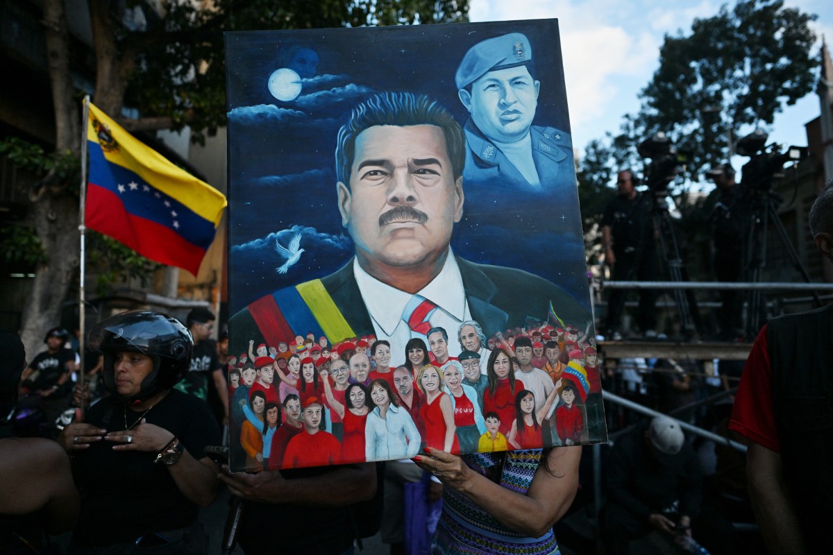 A woman shows a painting depicting ousted Venezuela's President Nicolas Maduro and former President Hugo Chavez (1999-2013) during a demonstration by supporters in Caracas on January 4, 2026, a day after he was captured in a US strike. Nicolas Maduro's congressman son called on January 4, 2026, for Venezuelans to take to the streets following his father's ouster by US forces and transfer to a New York jail. (Photo by Juan BARRETO / AFP)