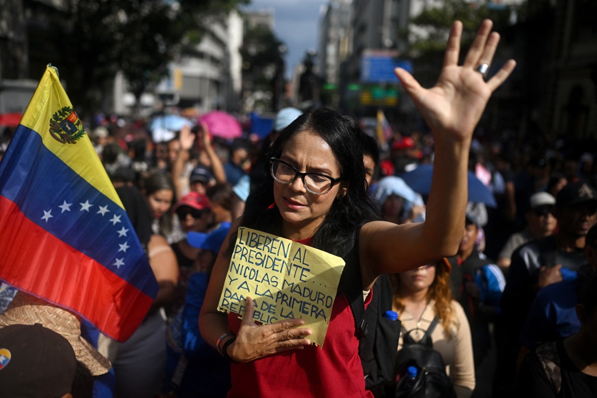 Mulher chora em manifestação enquanto segura um cartaz pedindo a libertação de Nicolas Maduro e Cilia Flores