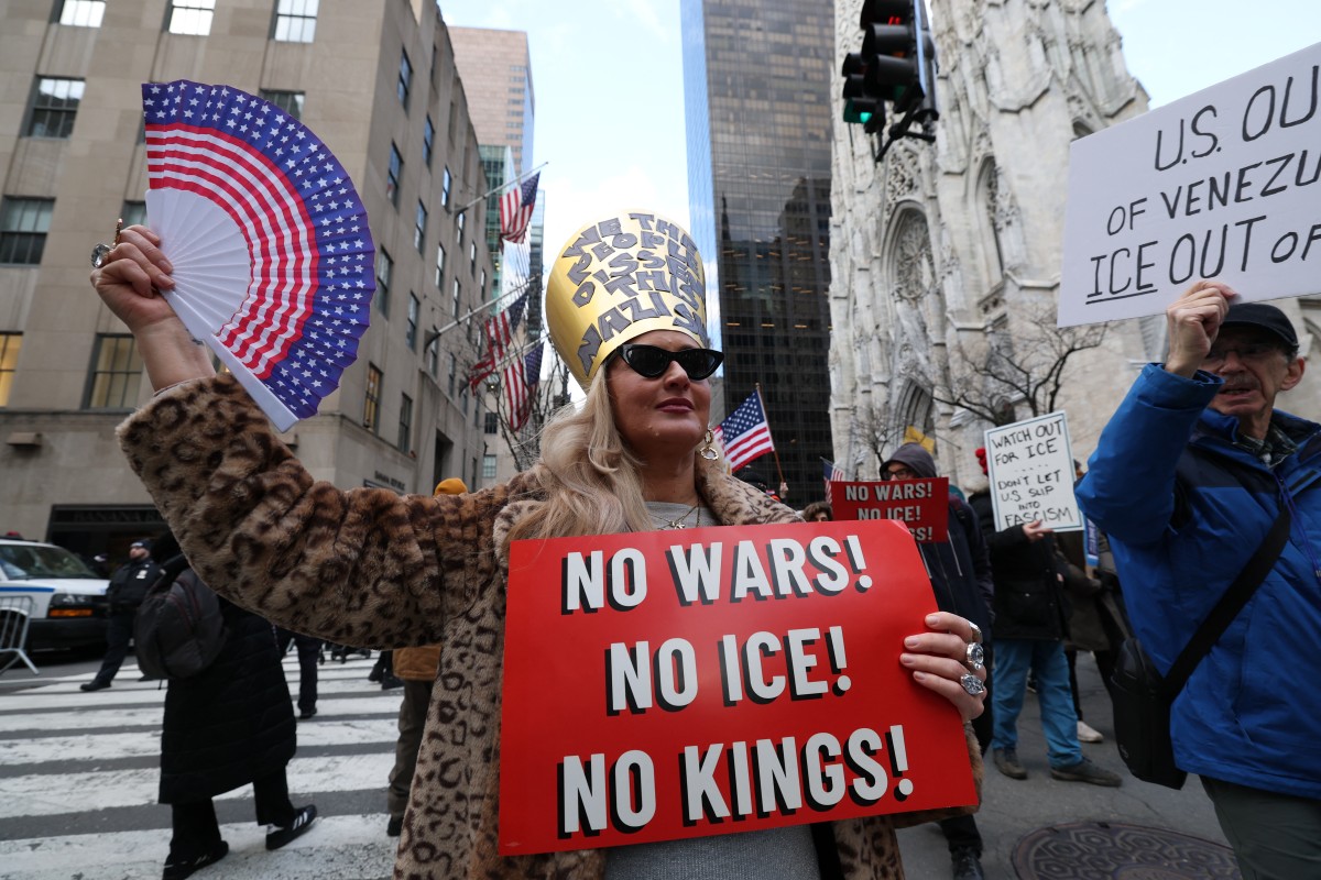 Pessoas seguram cartazes durante um protesto contra as atividades do Serviço de Imigração e Alfândega dos EUA (ICE), em 11 de janeiro de 2026 | Crédito: Timothy A. Clary/AFP