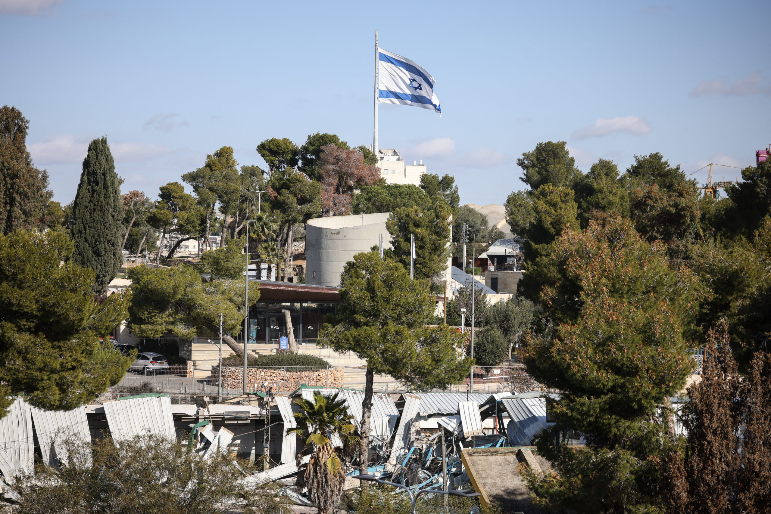 Bandeira de Israel sobre estruturas demolidas da Agência das Nações Unidas de Assistência aos Refugiados da Palestina no Oriente Próximo (UNRWA) em Jerusalém Oriental