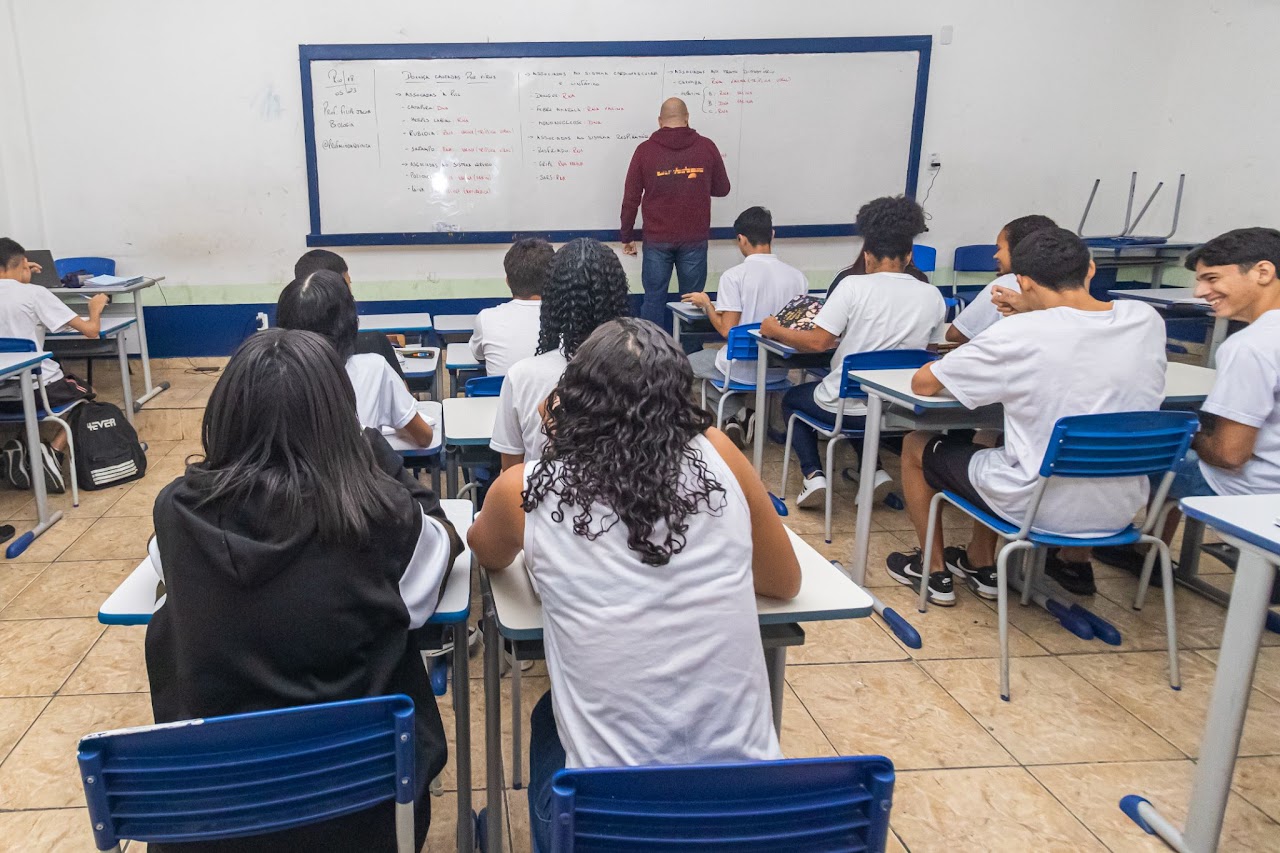 Estudantes observam anotações do professor em quadro branco