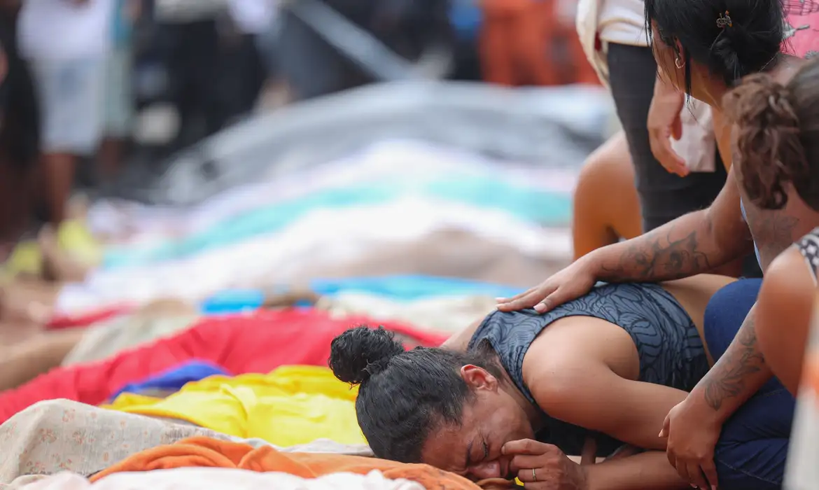 Em uma fileira de corpos expostos após a chacina mais letal do país, na Penha, zona norte do Rio, mulher chora sobre o corpo do marido assassinado