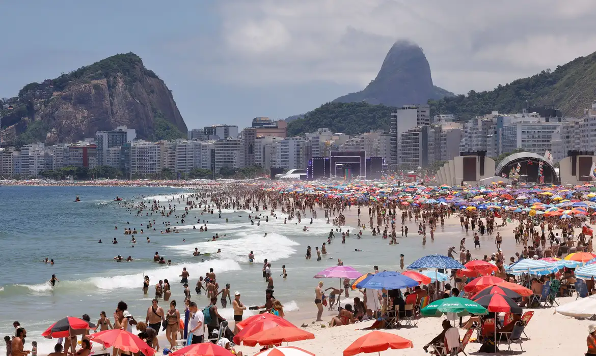 Praia cheia com palcos montados na areia da Praia de Copacabana no último dia do ano
