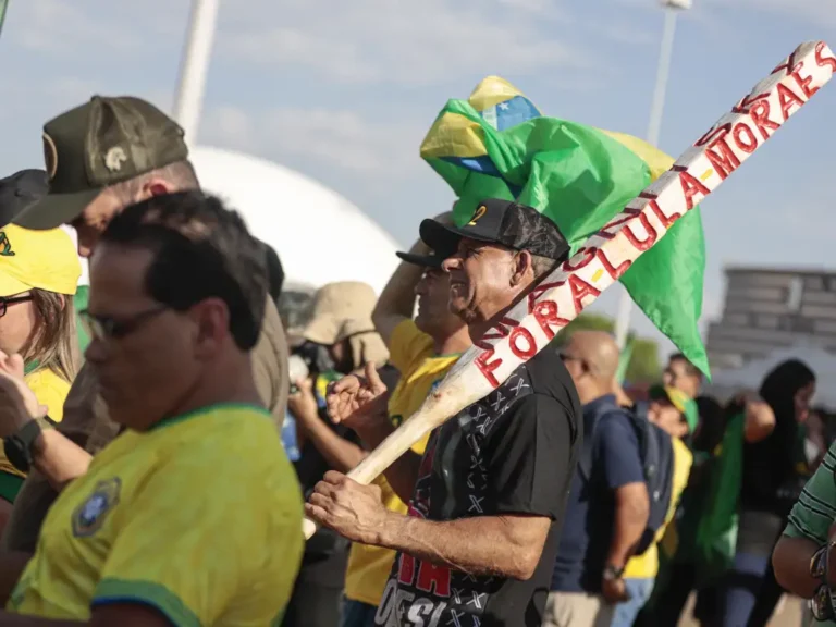 Manifestante de extrema-direita carrega um “porrete” no qual se lê “Fora Lula Moraes”