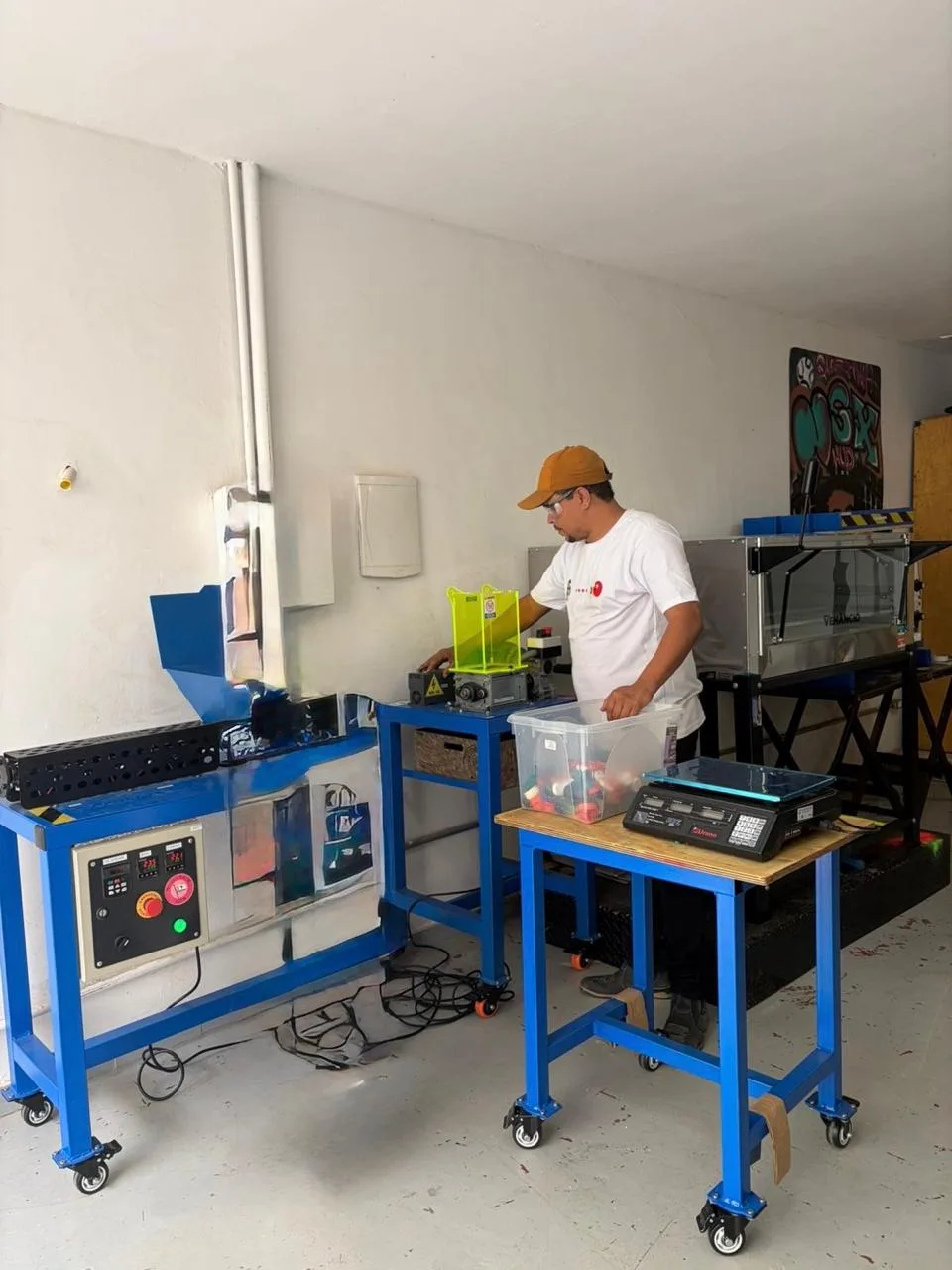 Paulo Henrique opera a trituradora que transforma resíduos plásticos em placas recicladas