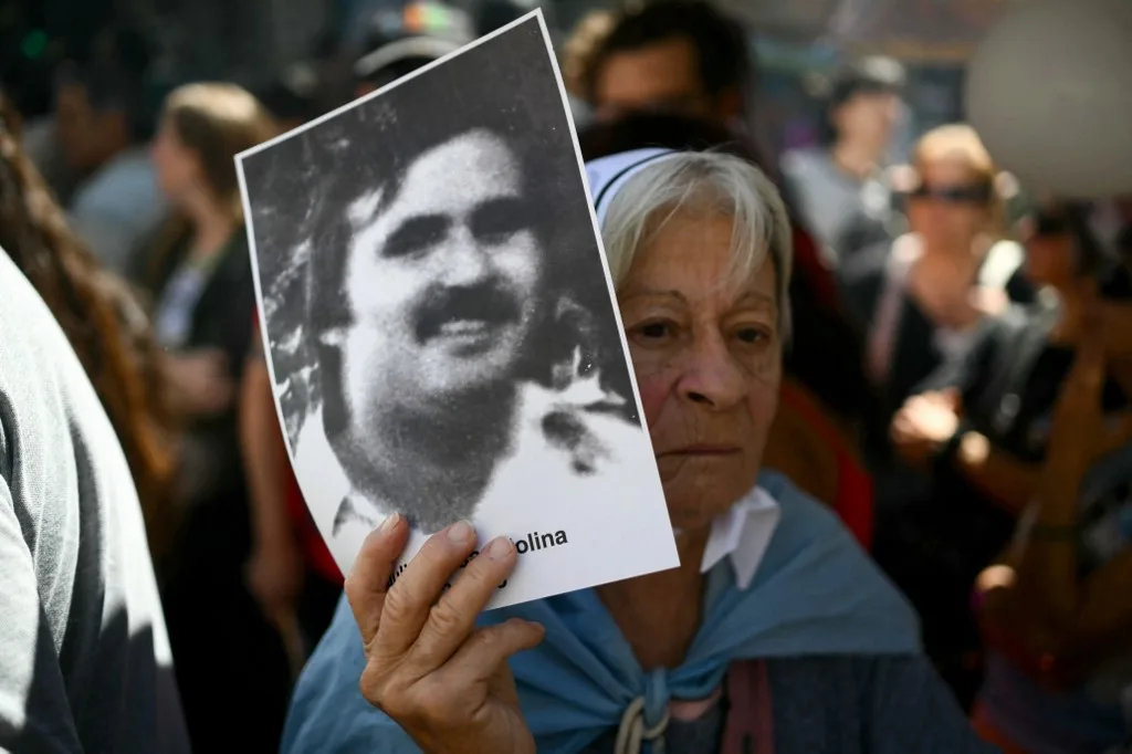 Uma mulher ergue um retrato de uma pessoa desaparecida durante uma marcha rumo à Praça de Maio, em Buenos Aires, em 24 de março de 2026, no 50º aniversário do início da última ditadura militar.