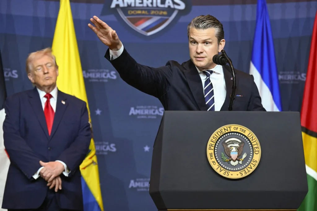 Trump acompanha fala do secretário de Defesa dos Estados Unidos, Pete Hegseth, durante a cúpula do Escudo das Américas, em Doral, na Flórida. Presença de Hegseth reforçou o tom militarizado da iniciativa anunciada por Trump em 7 de março (Foto: Saul Loeb/AFP)