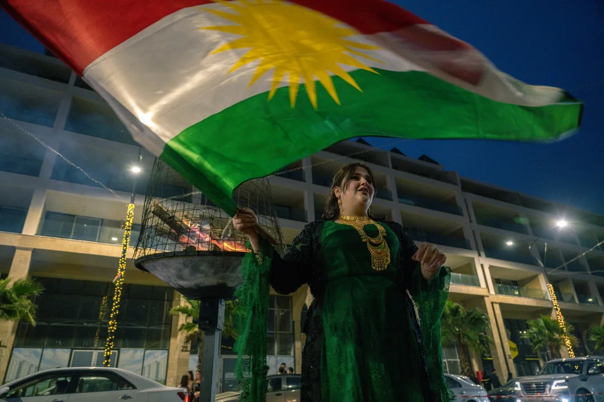 Mulher vestindo trajes tradicionais acena com a bandeira da região autônoma curda do Iraque enquanto celebra o Newroz em Sulaimaniyah, na região autônoma curda do Iraque, em 20 de março de 2026