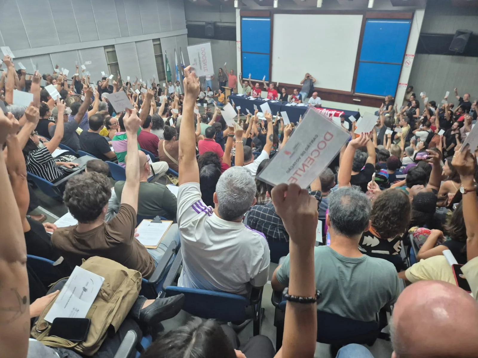 Em auditório lotado, professores erguem os braços em voto favorável à paralisação