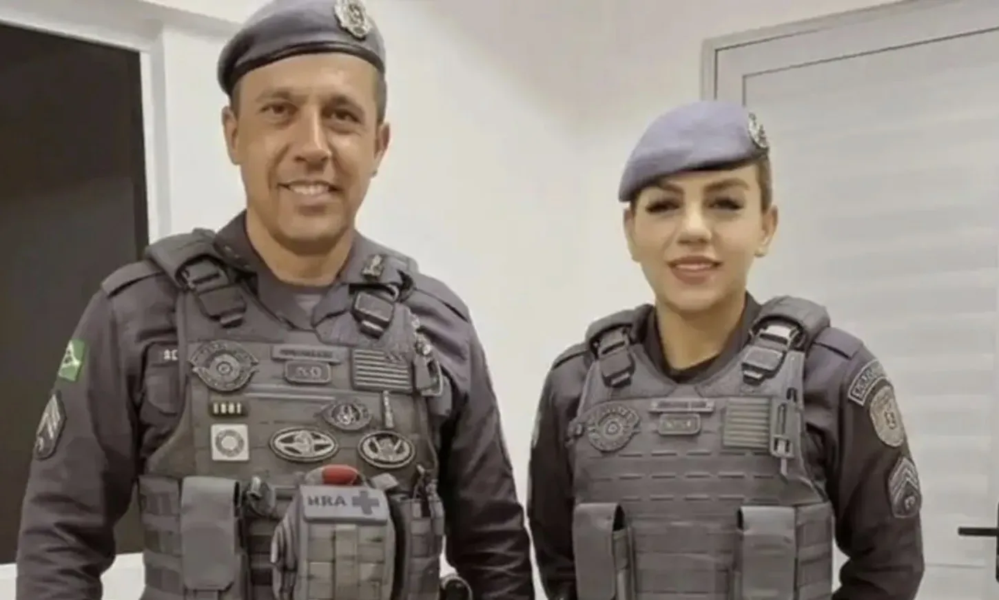 Imagem mostra marido e mulher sorrindo e vestidos com farda policial.