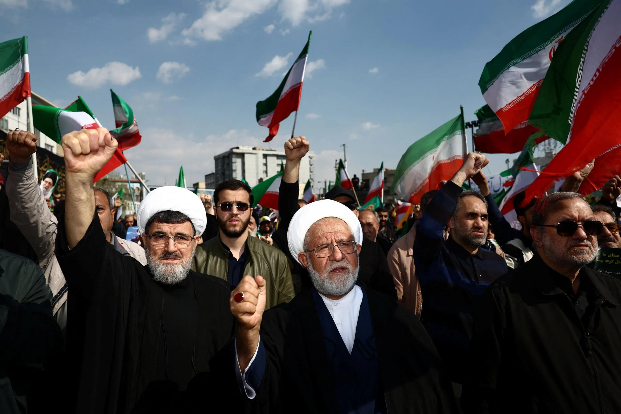 Uma mulher segura um cartaz com estêncil dos históricos líderes supremos iranianos, incluindo Mujahidin Khamenei, em um comício pró-Hezbollah em Beirute, Líbano