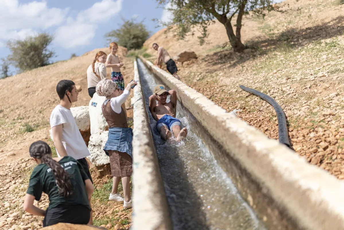 Colonos israelenses brincam em água desviada de nascentes palestinas no território semiárido a desértico da Cisjordânia