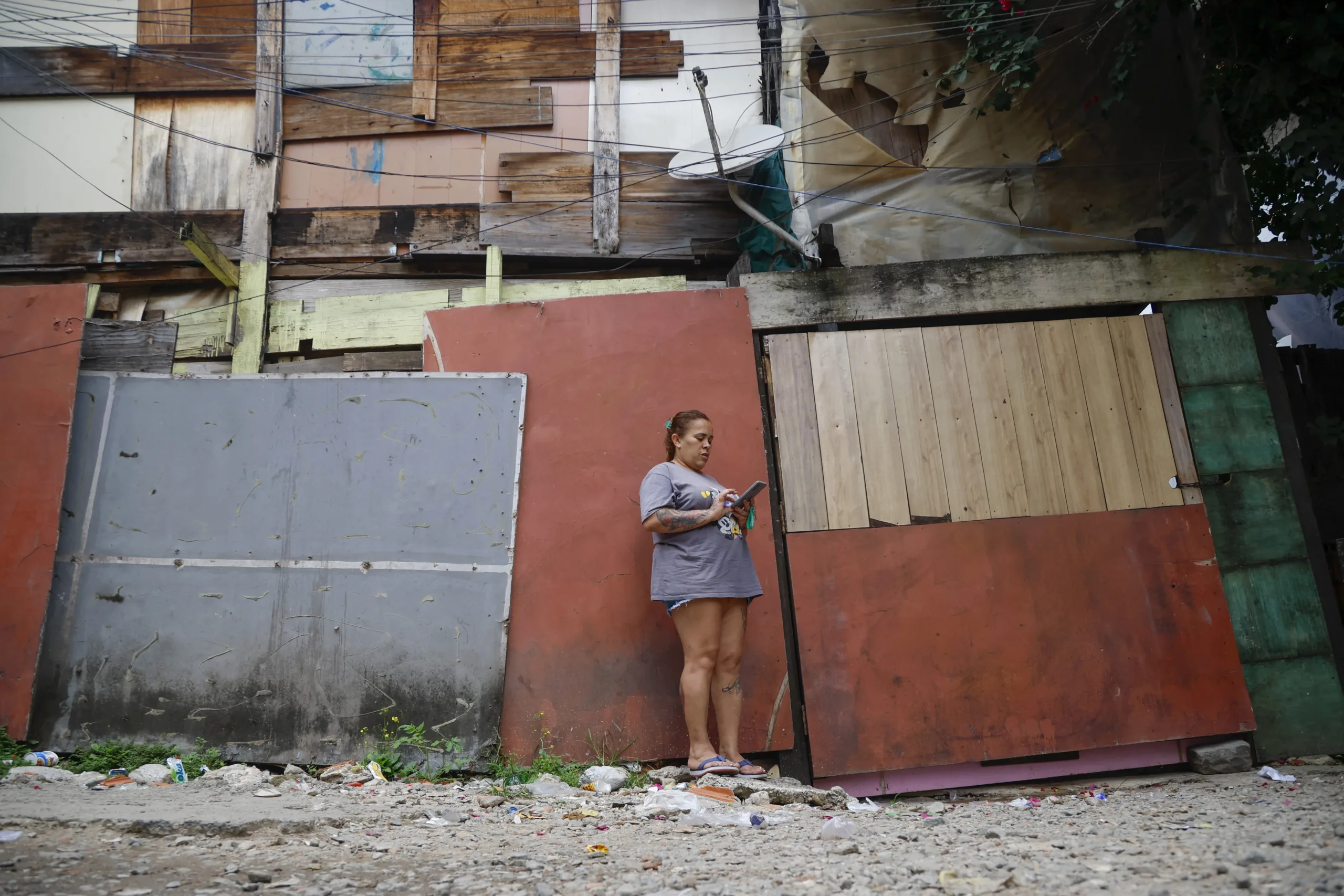A woman looks at her mobile phone at the Moinho favela during the state government's plan to evict the residents of the community in Sao Paulo, Brazil on April 22, 2025. (Photo by Miguel SCHINCARIOL / AFP)