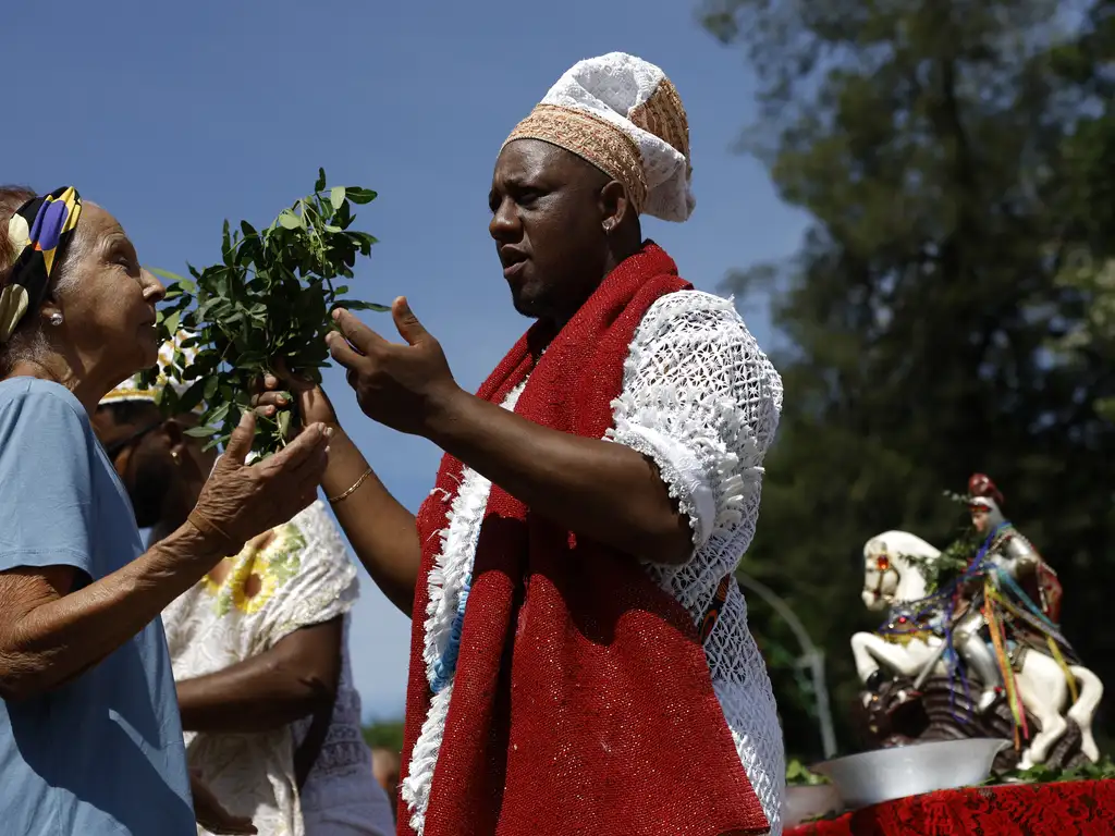 Babalorixá Luiz Alberto de Oxóssi, do candomblé, oferta bençãos a devotos durante as celebrações ao Dia de São Jorge, no centro do Rio