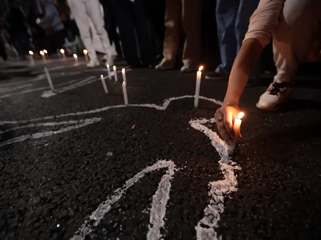 Manifestantes desenham silhueta de corpos humanos no asfalto e colocam velas em seu contorno para protestar contra a violência policial