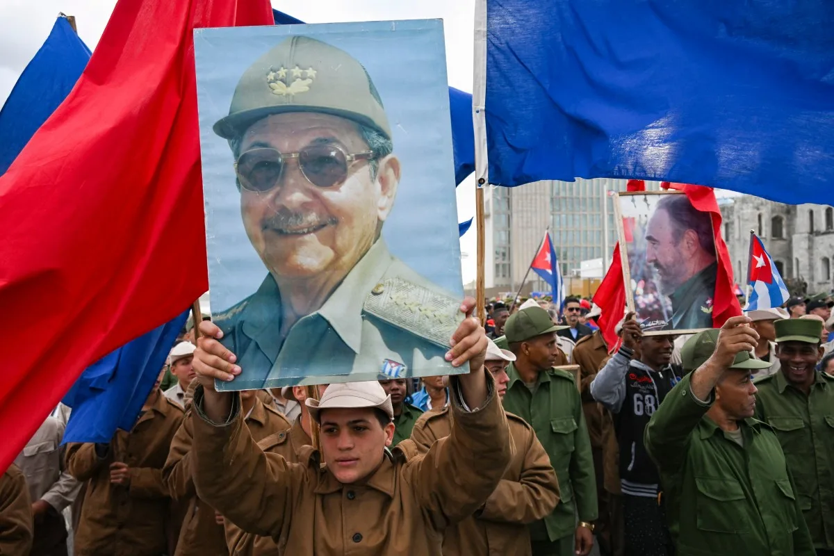 Membros das forças armadas seguram imagens do ex-presidente cubano Raúl Castro.