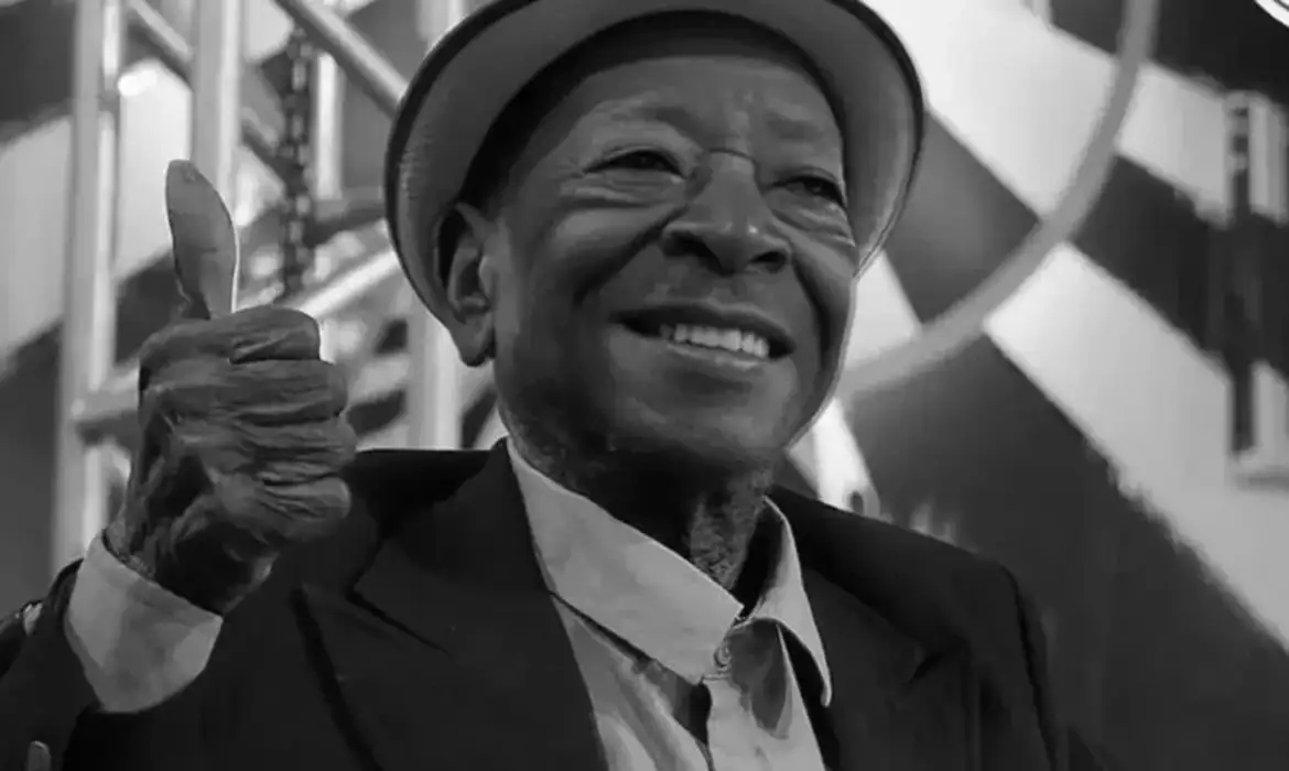 Foto em preto de branco de Noca da Portela, homem negro, usa chapéu panamá, terno e gravata