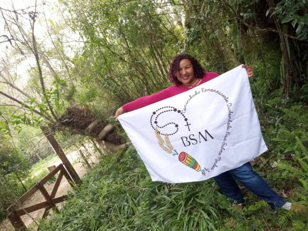 Vanessa Rodrigues Freitas segura a bandeira do Quilombo Bisa Sabina, desenhada por ela com símbolos da ancestralidade da comunidade