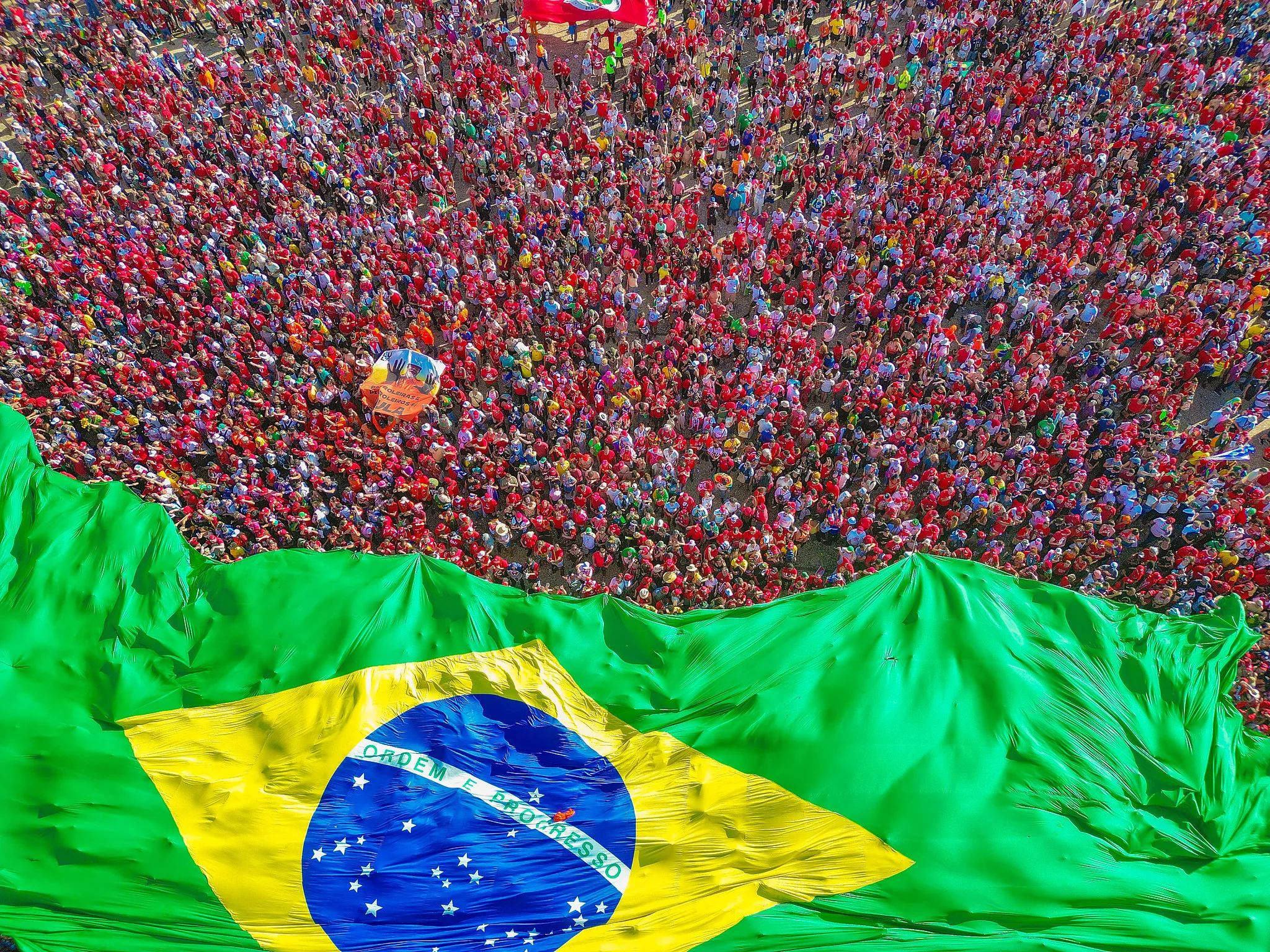 Bandeira brasileira estendida carregada pelas pessoas durante cerimônia de posse de o presidente Lula, em 2023