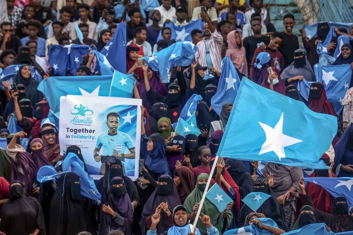 Apoiadores do árbitro somali Omar Abdulkadir Artan seguram bandeiras e cartazes durante recepção em Mogadíscio, nesta quarta-feira (10), antes de partida de solidariedade. (Foto: Hassan Ali Elmi/AFP)