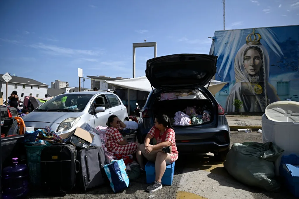 Moradores sentam-se ao lado de seus pertences, perto de um carro, enquanto se abrigam em uma rua após o terremoto em Catia La Mar, estado de La Guaira, a cerca de 30 km a noroeste de Caracas, em 25 de junho de 2026.