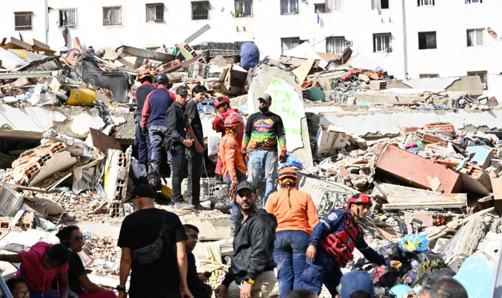 Membros da Defesa Civil venezuelana, bombeiros e voluntários trabalham no local de um prédio que desabou após os terremotos em Caraballeda, estado de La Guaira, Venezuela, em 26 de junho de 2026