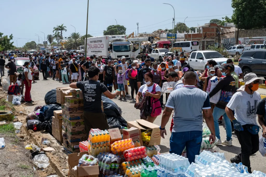 Em Caraballeda, estado de La Guaira, Venezuela, em 27 de junho de 2026, pessoas fazem fila para receber alimentos e bebidas doados após os terremotos