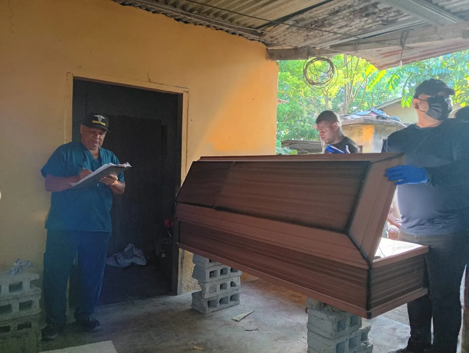 Funcionários do Ministério Público e da Medicina Forense locais preparam caixão para um dos corpos das vítimas do massacre. (Foto: Ministério Público da República de Honduras)