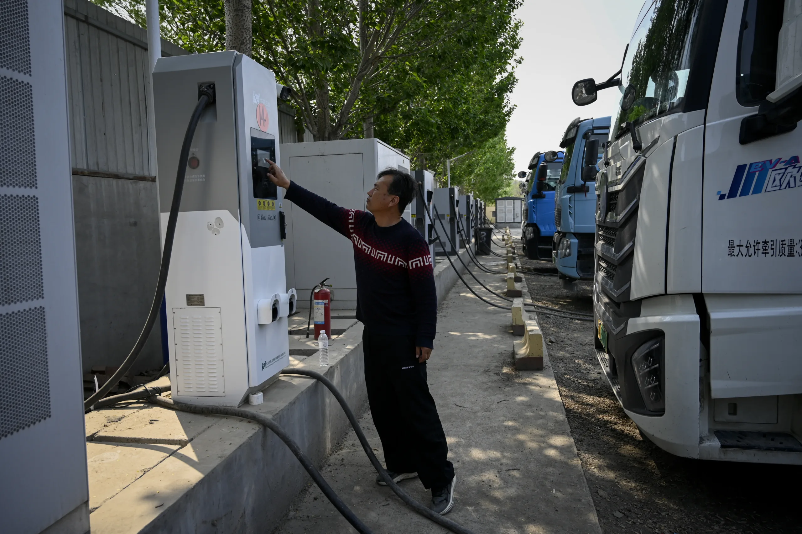 Motorista verifica o status de seu caminhão elétrico em uma estação de recarga em Pequim. 23 de abril de 2026.