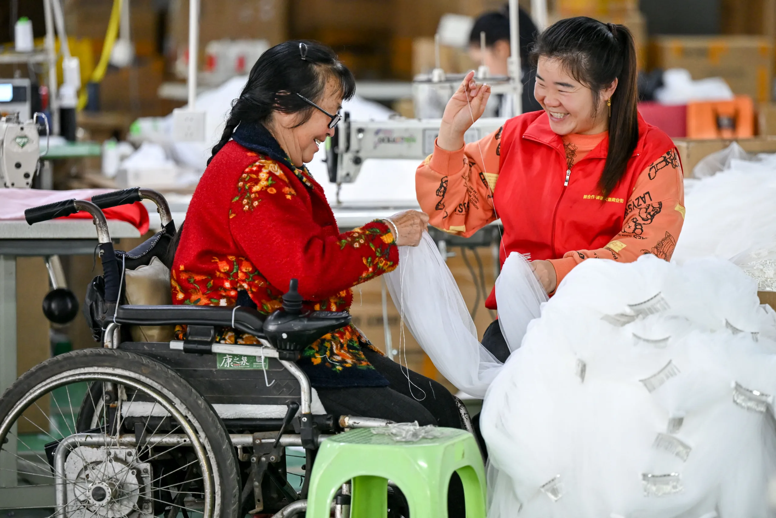 Uma voluntária interage com uma mulher com deficiência em uma oficina em um local de reassentamento para o combate à pobreza no distrito de Zixing, condado de Kaiyang, província de Guizhou, em 16 de maio de 2026.