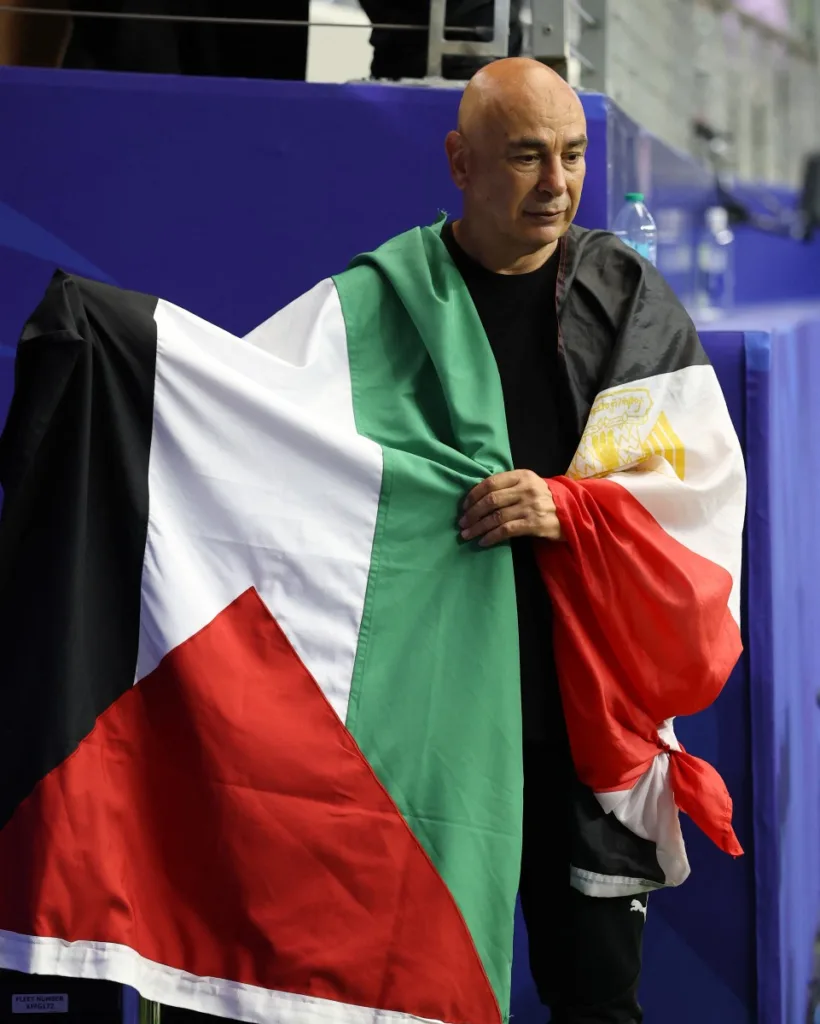 Hossam Hassan, técnico da seleção egípcia, segura a bandeira da Palestina após a vitória da equipe nos pênaltis durante a partida das oitavas de final da Copa do Mundo