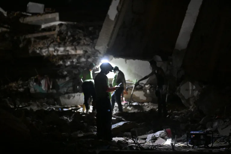 Um socorrista verifica um telefone celular em meio aos escombros de edifícios desabados em Caraballeda, estado de La Guaira, Venezuela, em 7 de julho de 2026, após os terremotos de 24 de junho. Os poderosos terremotos gêmeos que atingiram a Venezuela em 24 de junho deixaram pelo menos 3.685 mortos e quase 17.000 feridos, informou o governo venezuelano em sua mais recente atualização oficial em 7 de julho.