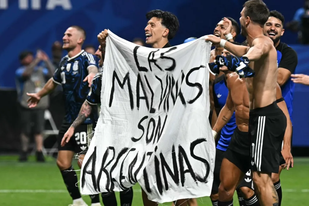 Jogadores da Argentina seguram uma faixa com a frase "As Malvinas (Ilhas Falkland) pertencem à Argentina" após vencerem a partida da semifinal da Copa do Mundo de 2026 entre Inglaterra e Argentina, no Atlanta Stadium, em Atlanta, em 15 de julho de 2026. (Foto de Paul ELLIS / AFP)