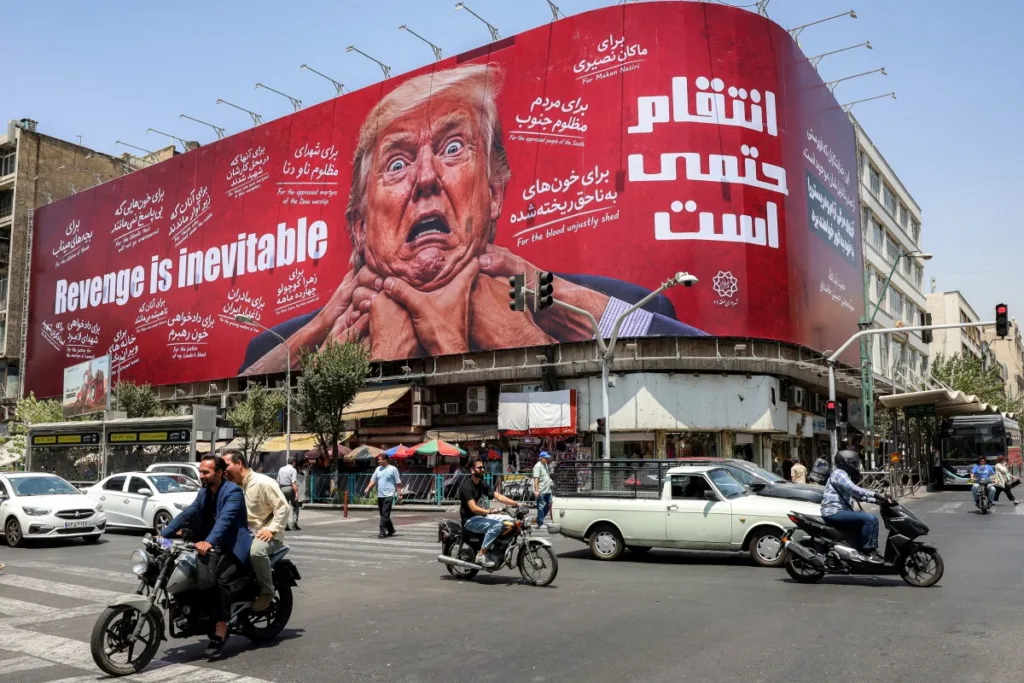 Motoristas passam por um grande outdoor prometendo vingança contra o presidente dos EUA, Donald Trump, no centro de Teerã