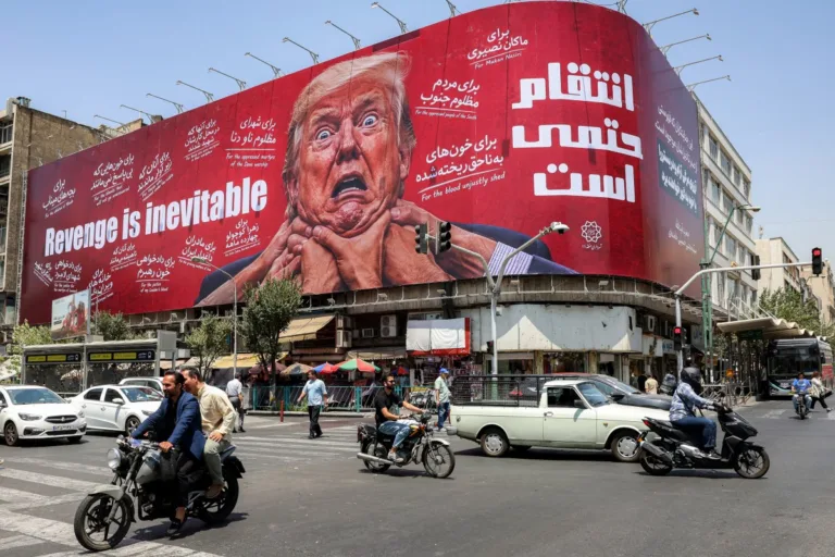 Motoristas passam por um grande outdoor prometendo vingança contra o presidente dos EUA, Donald Trump, no centro de Teerã
