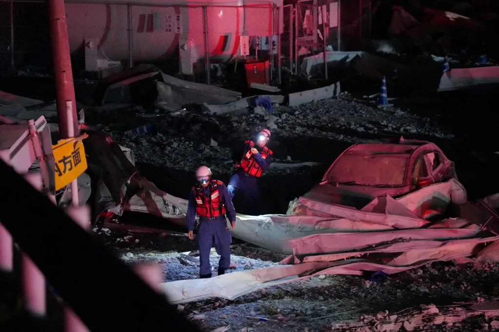 Bombeiros caminham pelo estacionamento do shopping Aeon Mall Kumamoto após uma explosão na cidade de Kashima, Japão, em 28 de julho de 2026. O centro comercial está entre os locais atingidos pelo terremoto na madrugada desta terça-feira.