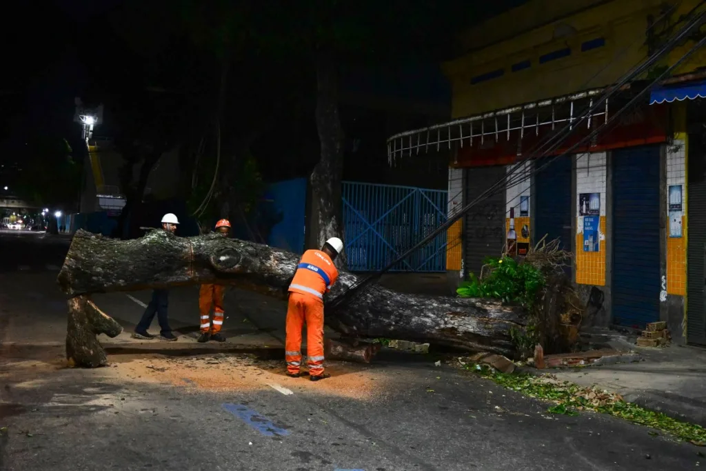 Trabalhadores municipais cortam e removem uma árvore caída em uma rua residencial após fortes rajadas de vento associadas à chegada de uma frente fria no Rio de Janeiro, Brasil, em 29 de julho de 2026.