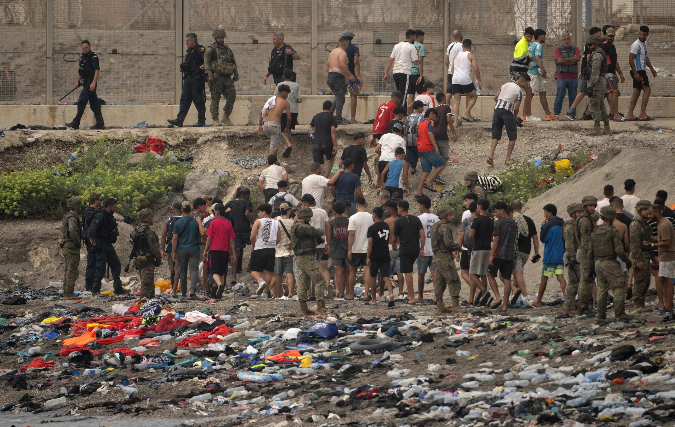 Soldados controlam enquanto imigrantes atravessam de volta ao Marrocos depois de cruzarem a fronteira para entrar na cidade espanhola de Ceuta, no Norte da África.