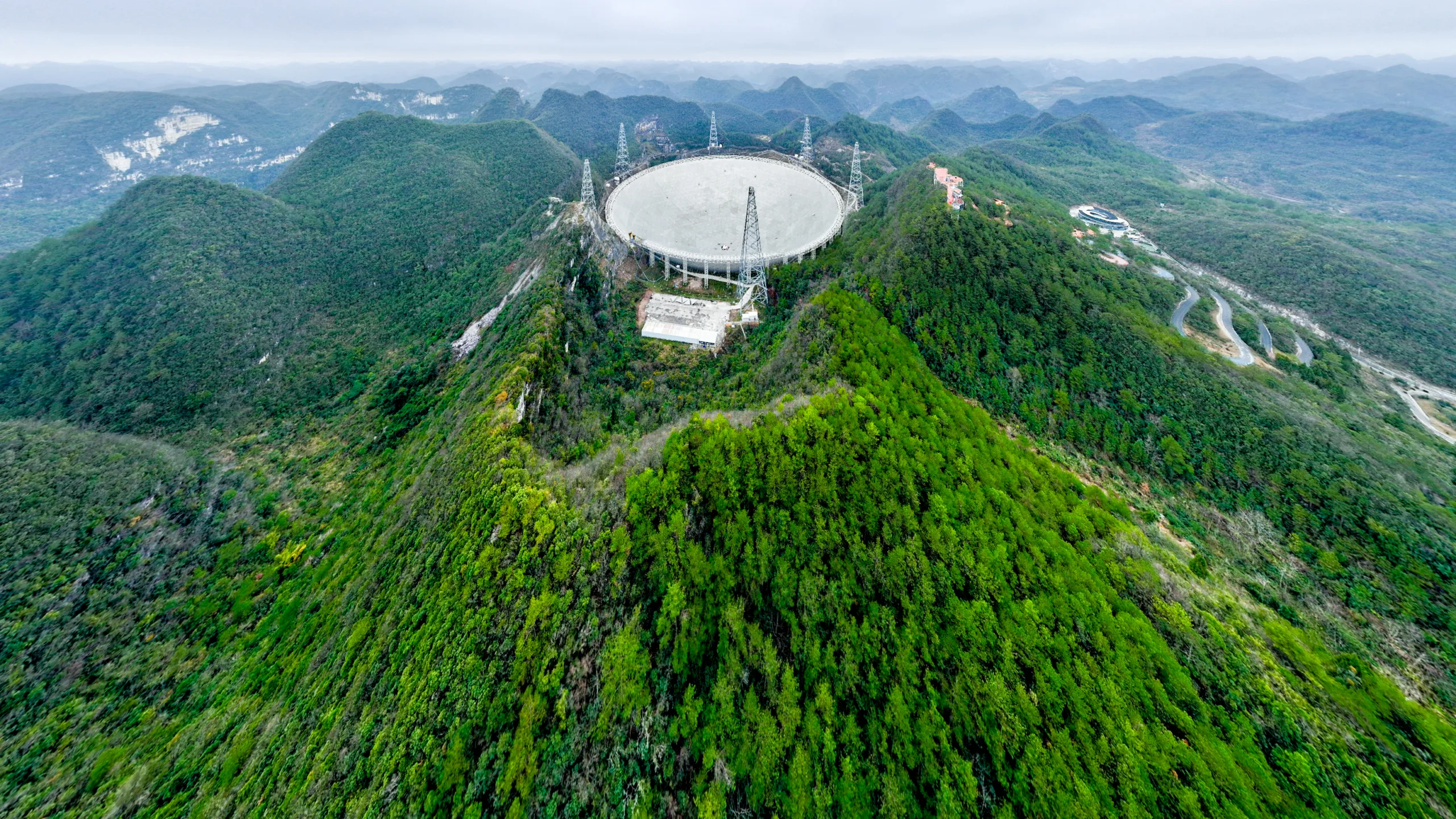 Uma foto panorâmica aérea tirada em 18 de fevereiro de 2025 mostra o Radiotelescópio Esférico de Abertura de Quinhentos Metros (FAST, na sigla em inglês) da China em manutenção na província de Guizhou, no sudoeste da China.