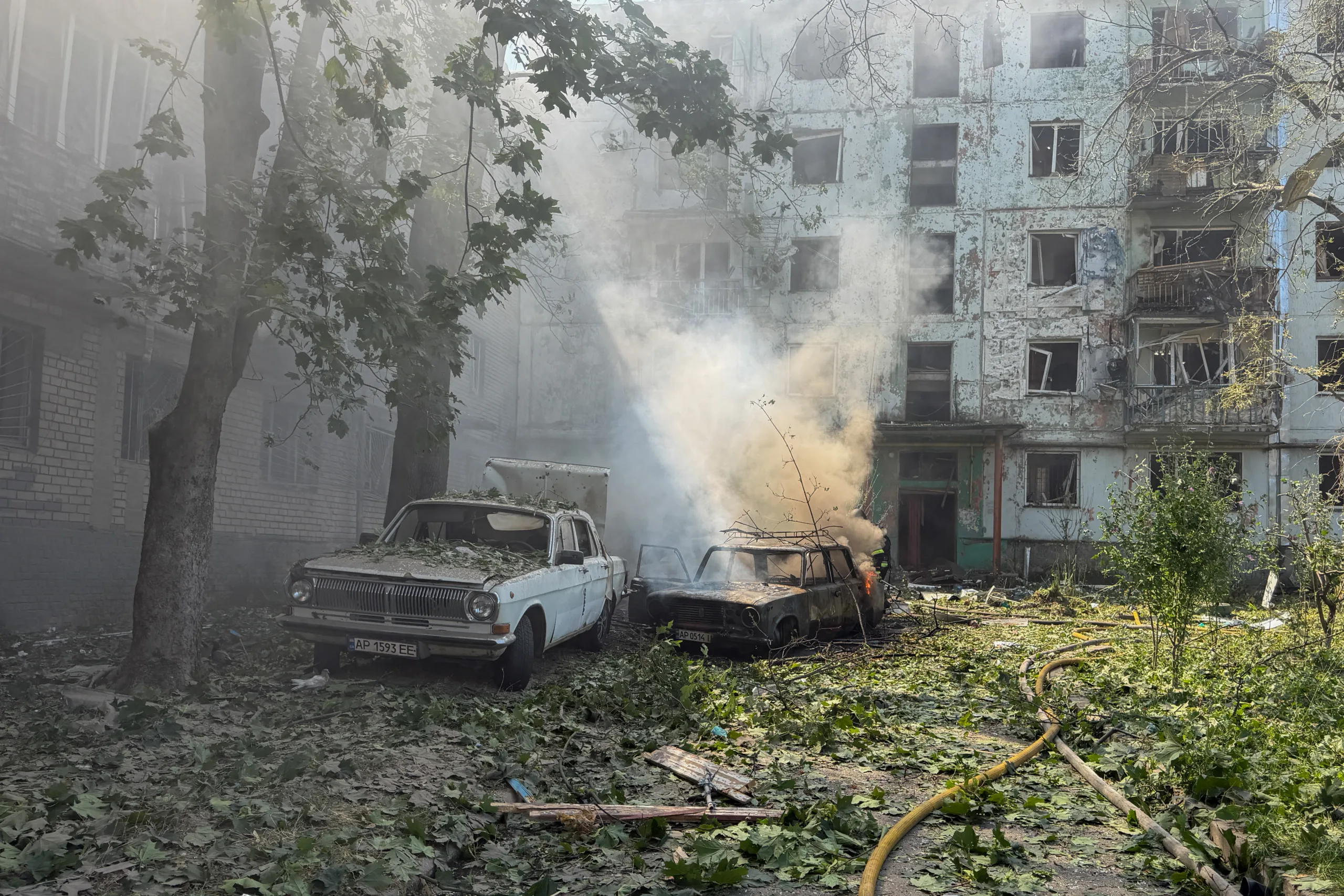 carros queimados ao lado de um edifício residencial danificado no local de um ataque aéreo russo em Zaporizhzhia, em agosto de 2026