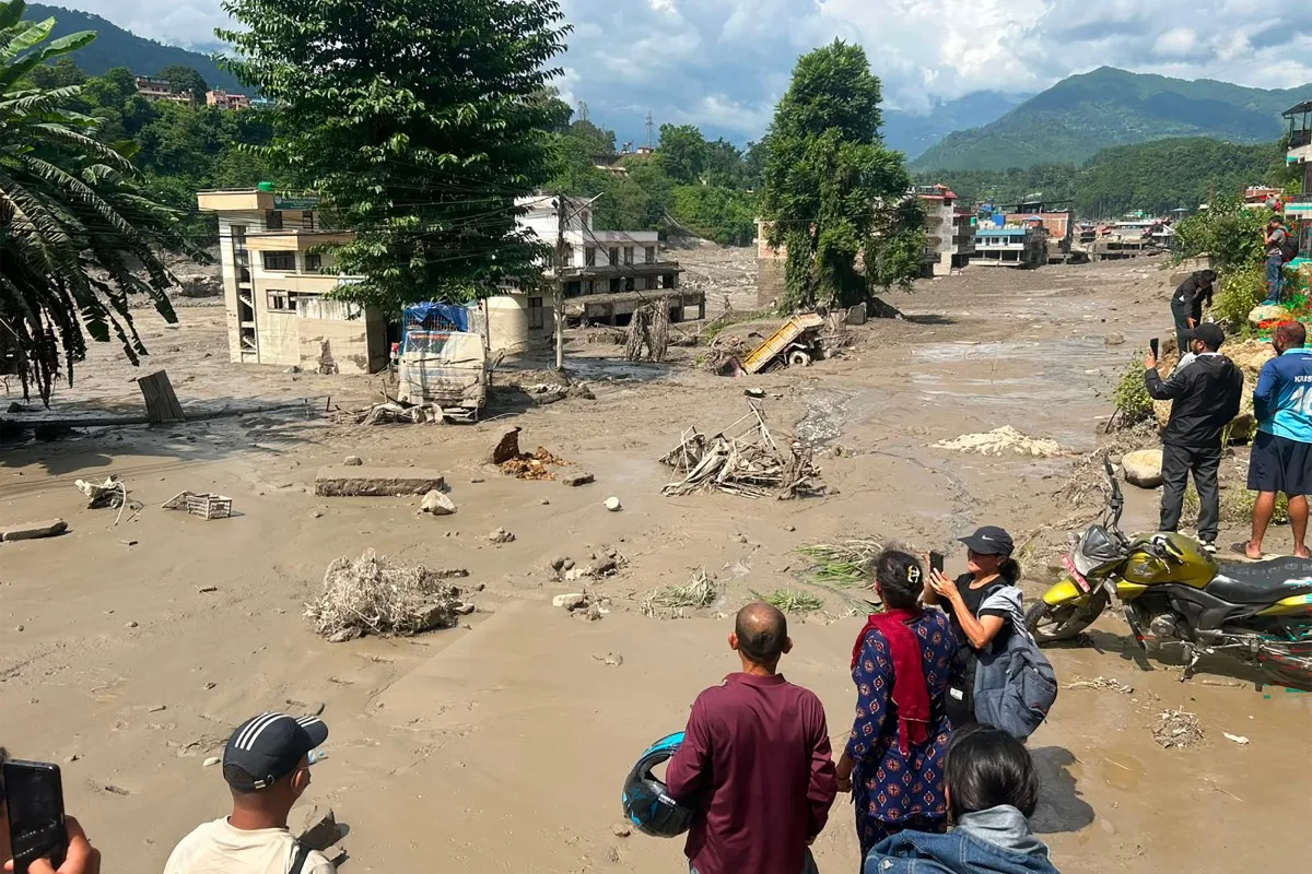 Moradores observam casas parcialmente submersas em água barrenta após enchentes repentinas em Trishuli Bazar, no distrito de Nuwakot, Nepal, em 26 de agosto de 2026.
