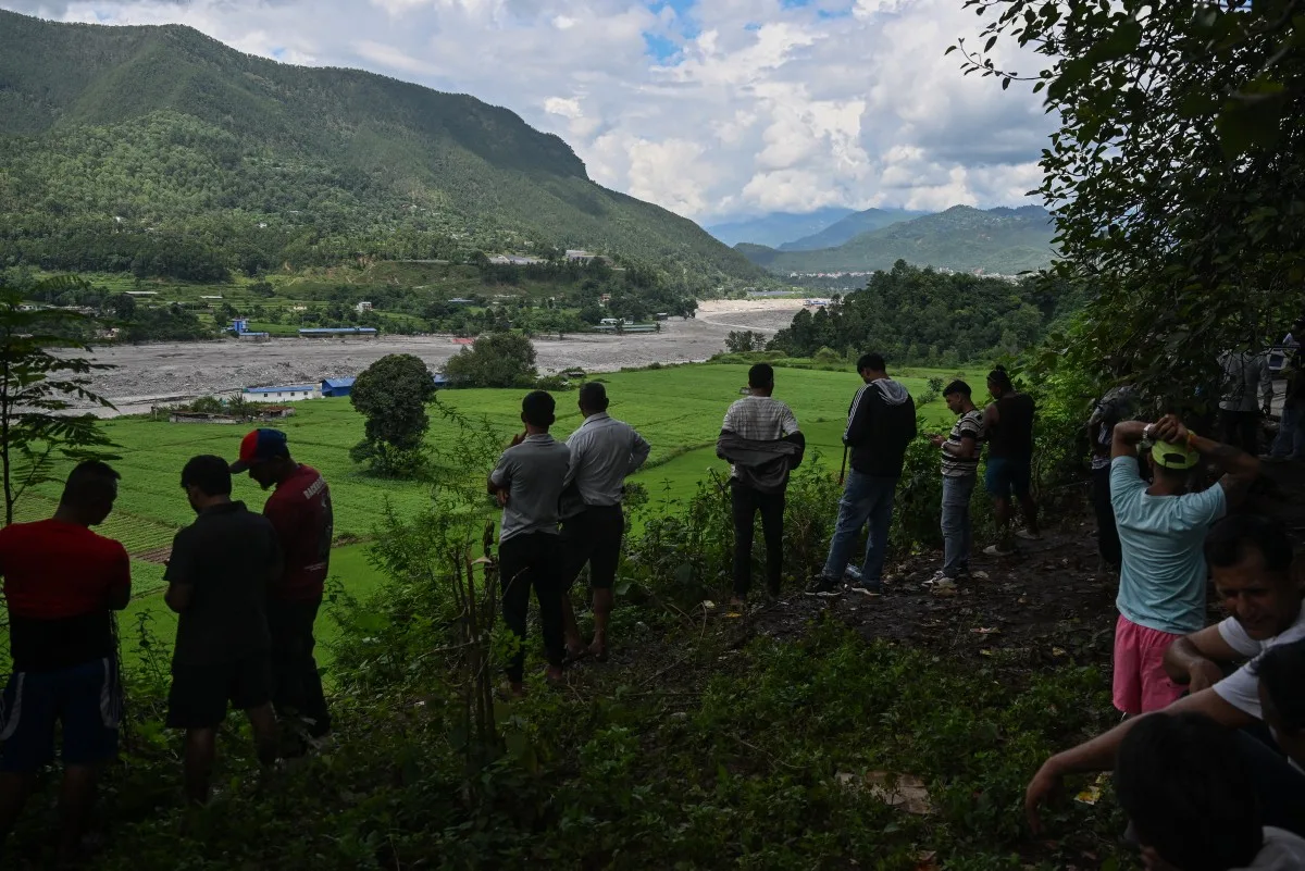 Moradores observam o rio Trishuli enquanto se abrigam em um local elevado após um alerta de inundação na área de Pipaltar, distrito de Nuwakot, Nepal, em 28 de agosto de 2026.