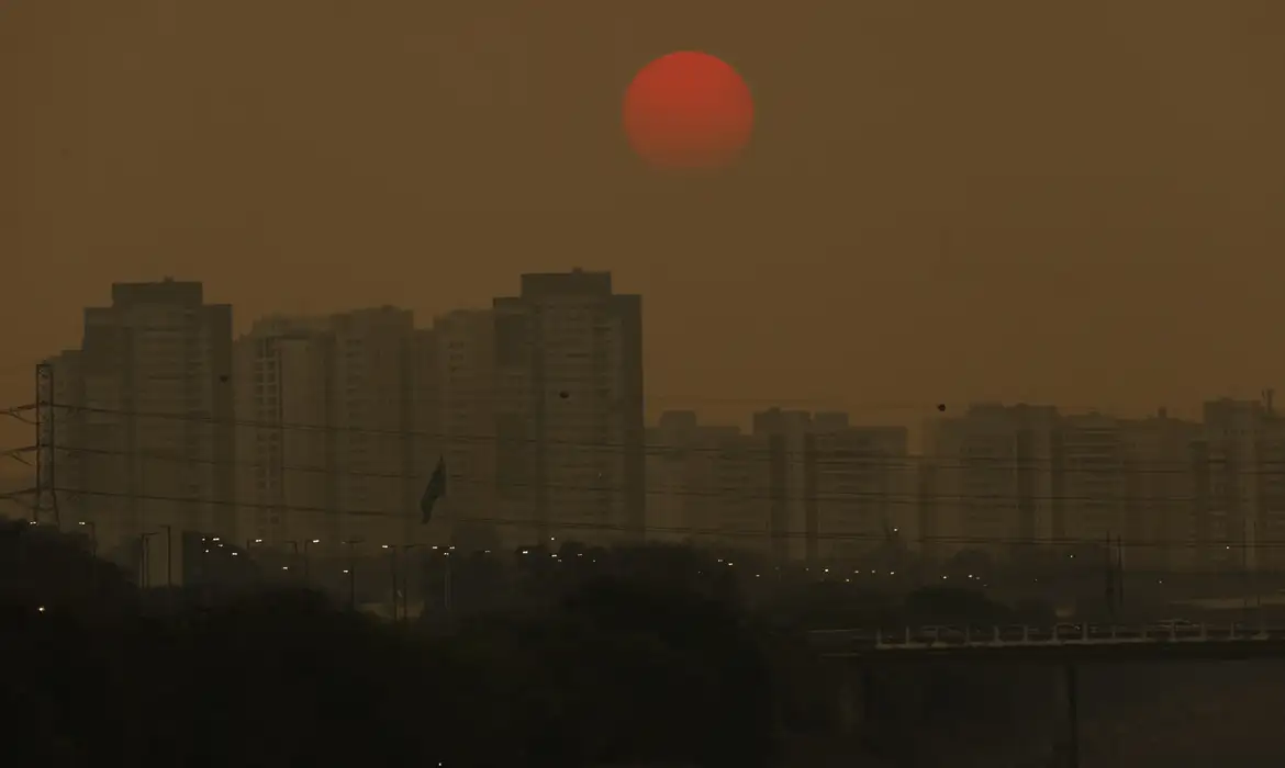 Fotografia de paisagem de um por do sol avermelhado por conta do excesso de poluição