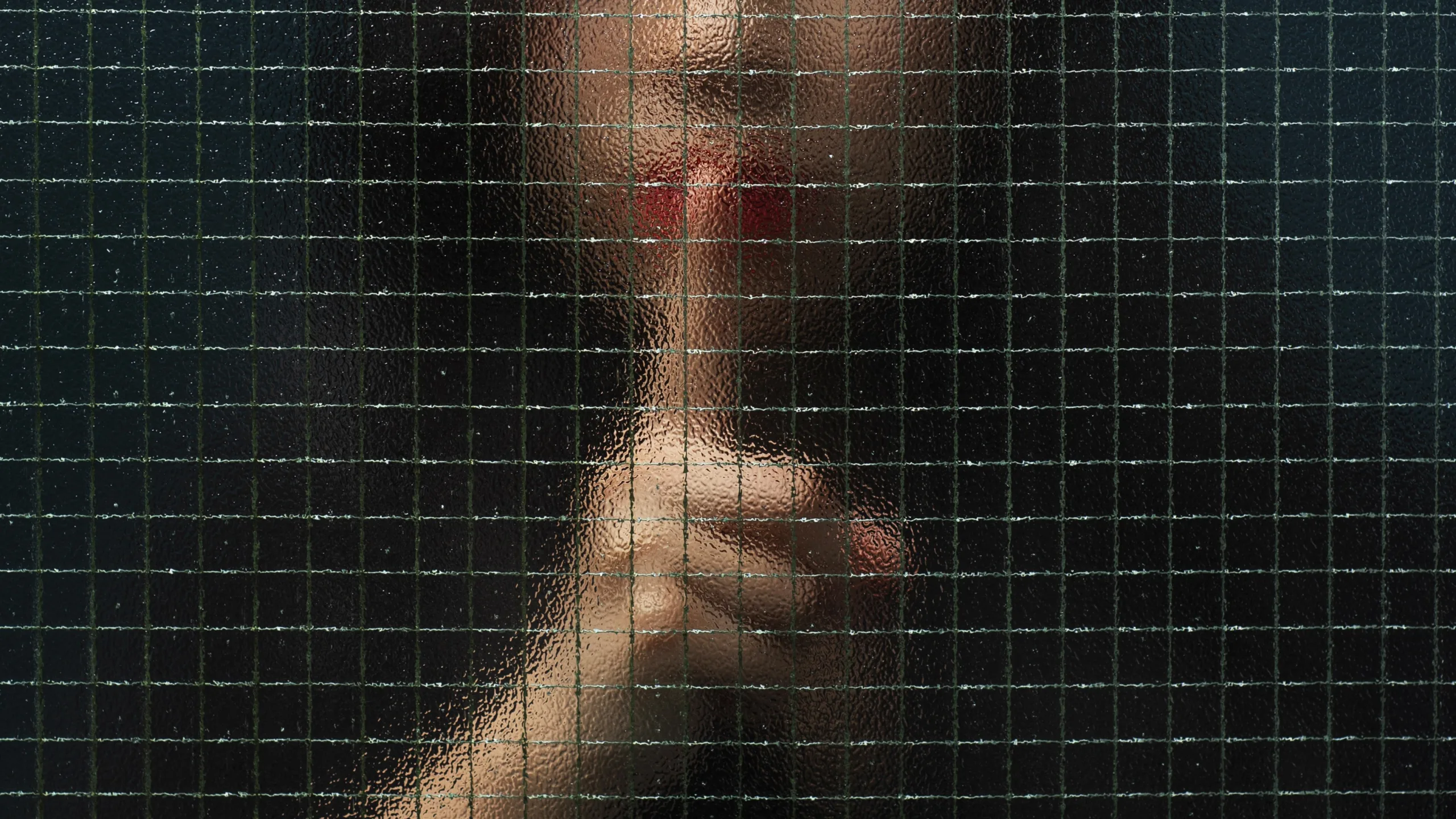 Fotografia borrada de uma mulher com um dedo na frente dos lábios, em um gesto como quem pede silêncio
