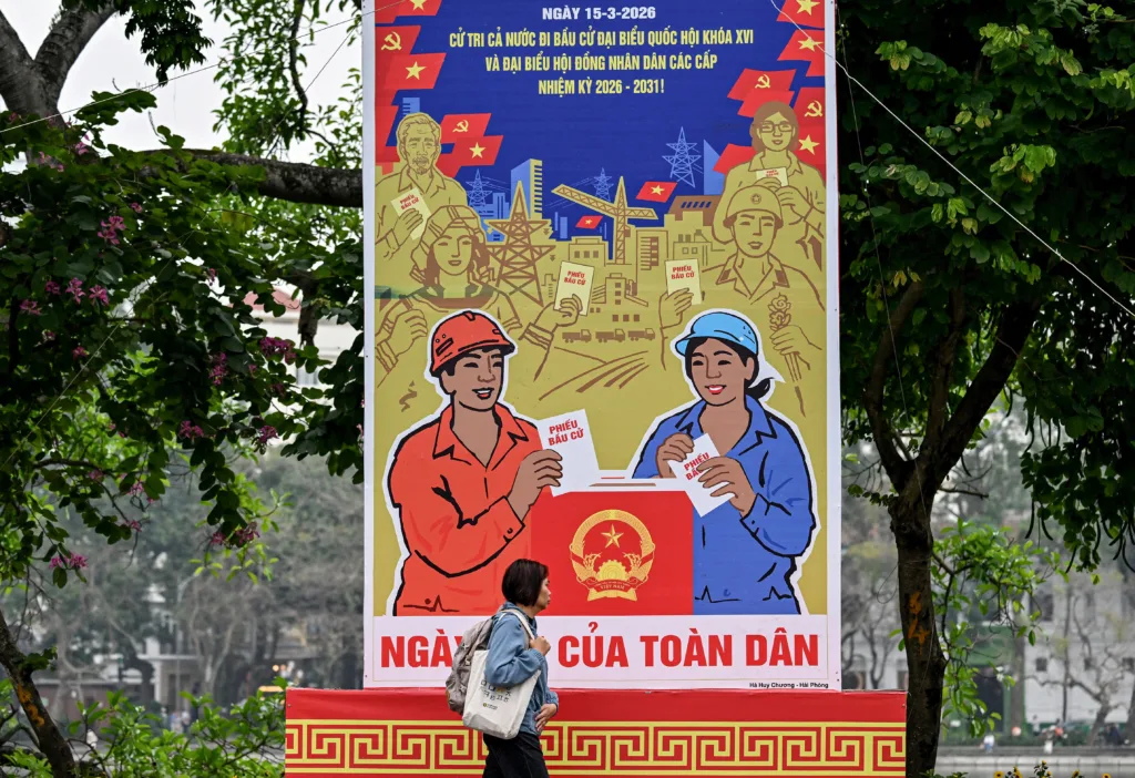 Mulher passa em frente a um cartaz das eleições para a Assembleia Nacional e os Conselhos Populares em Hanói, capital do Vietnâ - 9 de março de 2026.