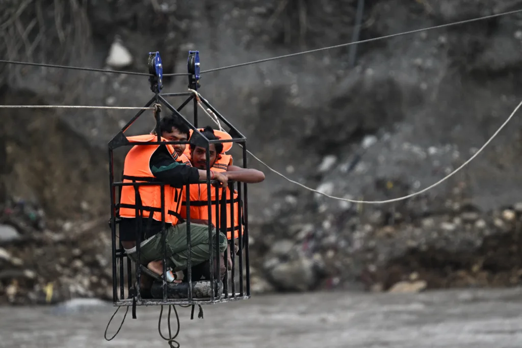 Sobreviventes atravessam o rio Tadi usando uma tirolesa após inundações no Nepal