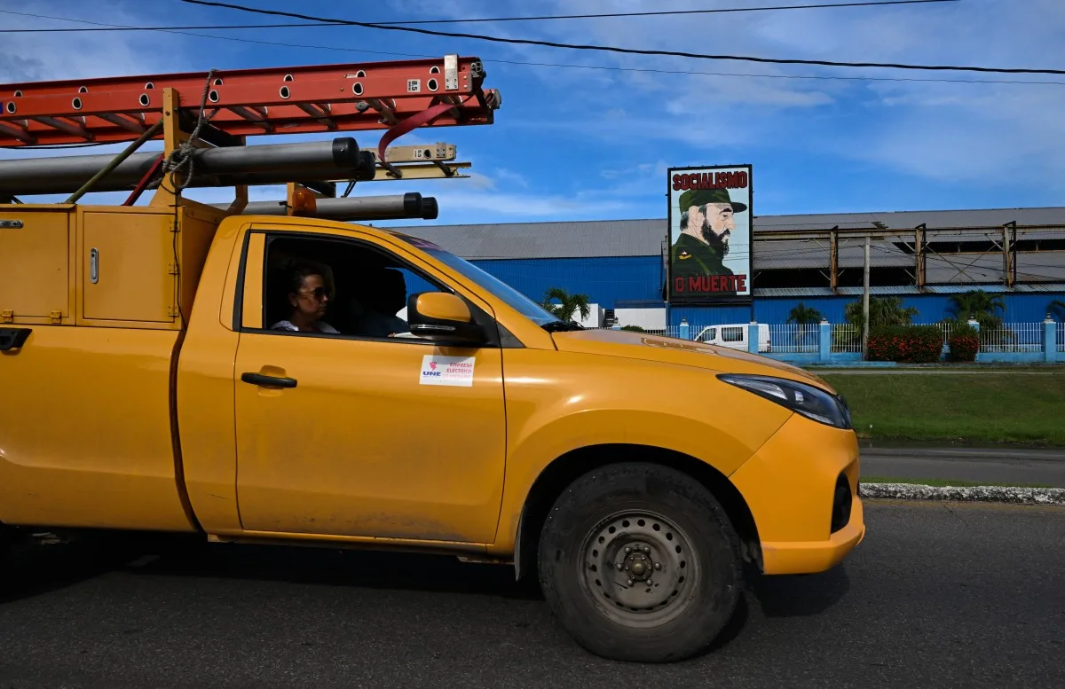 Um caminhão pertencente à empresa de eletricidade passa diante de um cartaz do falecido líder Fidel Castro durante um apagão nacional em 18 de setembro de 2026.