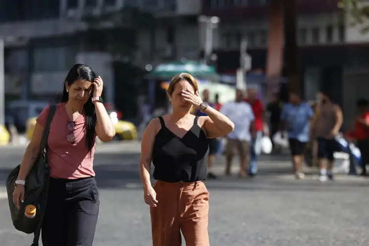 Pessoas se protegem do sol no centro da cidade em dia de calor no Rio de Janeiro.