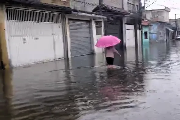 Morador caminha por rua alagada na Vila Seabra, na zona leste de São Paulo